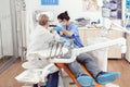 Sick man lying on stomatological chair while senior doctor taking care of tooth health