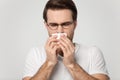 Sick millennial guy caught cold, sneezing, feeling unwell.