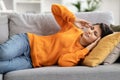 Sick millennial indian woman lying on couch, feel dizzy, migraine