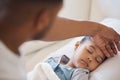 Sick mixed race girl lying asleep in bed at home. Worried father using his hand to feel the high body temperature on his