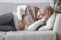 Sick Muslim Woman Having Abdominal Pain, Lying On Couch At Home