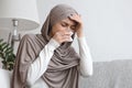 Sick muslim woman in hijab having runny nose and headache