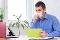 Sick office worker in medical mask sits at desk