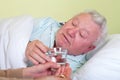 Sick old man in bed, receiving his pills Royalty Free Stock Photo