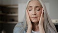Sick old mature caucasian woman worried tired upset retiree grey-haired lady holding head massaging temples unbearable Royalty Free Stock Photo