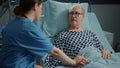 Sick old patient getting help from nurse in hospital ward