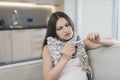 Sick pregnant woman sitting at home on the couch. It measures temperature with an electronic thermometer Royalty Free Stock Photo