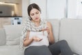 Sick pregnant woman sitting at home on the couch. She`s getting ready to drink a pill.