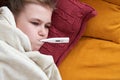 Sick preteen girl laying in bed using thermometer