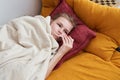 Sick preteen girl laying in bed using thermometer