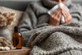 Sick senior man blowing his nose while sitting on a sofa, essential oils bottle on the table Royalty Free Stock Photo