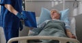 Sick senior man lying in hospital bed and signing informed consent
