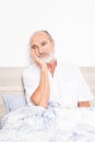 Sick senior sitting on bed with a strong headache Royalty Free Stock Photo