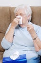 Sick senior with thermometer blowing her nose Royalty Free Stock Photo