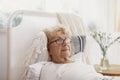 Sick senior woman with glasses lying in hospital bed Royalty Free Stock Photo