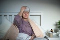 Sick senior woman with headache in bed at home, headache and side effects of vaccination effects. Royalty Free Stock Photo