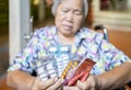 Sick senior woman holding medicine pills in wheelchair,sad female elderly showing a lot of drugs,medication to treatment her