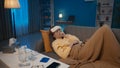 A sick suffering woman lies with a compress on her head on a sofa in the living room. The woman is choking with a cough