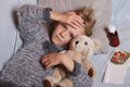 Sick little girl lying in the bed with her toy. Child winter flu allergy health care concept