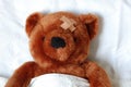 Sick teddy with injury in bed