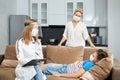 Sick teenager boy lying on sofa while doctor doing checkup Royalty Free Stock Photo