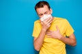 Sick tired man wearing medical mask and coughs isolated on blue background. Coronavirus, Covid-19, illness person, sore throat