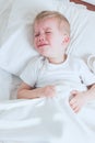 Sick toddler boy crying in bed