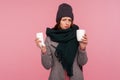 Sick unhealthy woman in scarf and hat holding in hands napkin and cup with hot tea, feeling chills Royalty Free Stock Photo