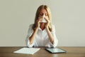 Sick upset exhausted woman sneezing blow nose using tissue while working with digital tablet computer and documents sitting at