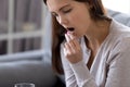 Sick upset woman holding glass of water, taking pill, close up