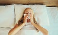 Sick upset woman sneezing blow nose using tissue lying in bed at home