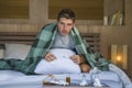 Sick wasted and exhausted man at home bed lying feeling unwell suffering cold and flu sneezing nose with tissues having virus and Royalty Free Stock Photo