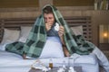 Sick wasted and exhausted man at home bed lying feeling unwell suffering cold and flu sneezing nose with tissues having virus and Royalty Free Stock Photo