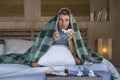 Sick wasted and exhausted man at home bed lying feeling unwell suffering cold and flu sneezing nose with tissues having virus and Royalty Free Stock Photo