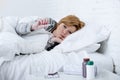 Sick woman in bed checking temperature with thermometer feeling feverish having cold winter flu virus Royalty Free Stock Photo