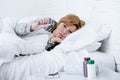 Sick woman in bed checking temperature with thermometer feverish weak suffering cold winter flu virus Royalty Free Stock Photo