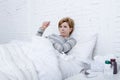 Sick woman in bed checking temperature with thermometer feverish weak suffering cold winter flu virus Royalty Free Stock Photo