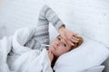 sick woman in bed checking temperature with thermometer feverish weak suffering cold winter flu virus Royalty Free Stock Photo