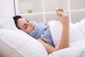 Sick woman in bed with thermometer is having high temperature/fever Royalty Free Stock Photo