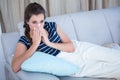 Sick woman blowing her nose on couch Royalty Free Stock Photo