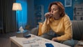 A sick woman drinks cough syrup, antipyretic or antiinflammatory. A woman is sitting in the living room on a sofa in