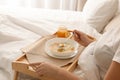 Sick woman eating fresh homemade soup to cure flu in bed at home