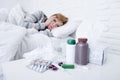 Sick woman feeling bad ill lying on bed suffering headache winter cold and flu virus having medicines Royalty Free Stock Photo