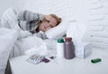 Sick woman feeling bad ill lying on bed suffering headache winter cold and flu virus having medicines Royalty Free Stock Photo