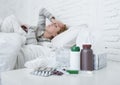 Sick woman feeling bad ill lying on bed suffering headache winter cold and flu virus having medicines Royalty Free Stock Photo