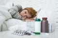 Sick woman feeling bad ill lying on bed suffering headache winter cold and flu virus having medicines Royalty Free Stock Photo