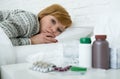 sick woman feeling bad ill lying on bed suffering headache winter cold and flu virus having medicines Royalty Free Stock Photo