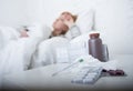 sick woman feeling bad ill lying on bed suffering headache winter cold and flu virus having medicines Royalty Free Stock Photo