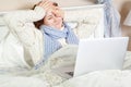 Sick woman feeling bad, resting and working with her laptop and internet in her bed at home Royalty Free Stock Photo