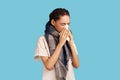 Sick woman feels unwell, blows nose in tissue, suffers from running nose, cold symptoms, allergy